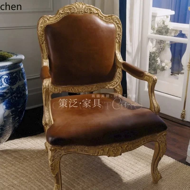 Vintage French style armchair with gold solid wood frame and brown genuine leather seating.