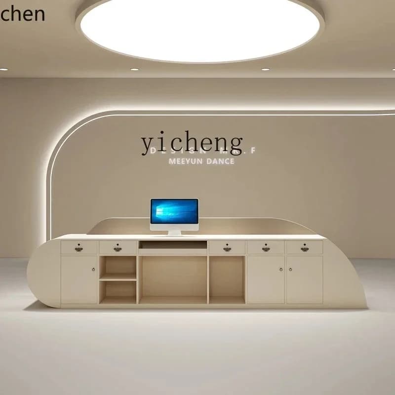 Modern cream-colored minimalist reception desk with storage drawers and curved edges.