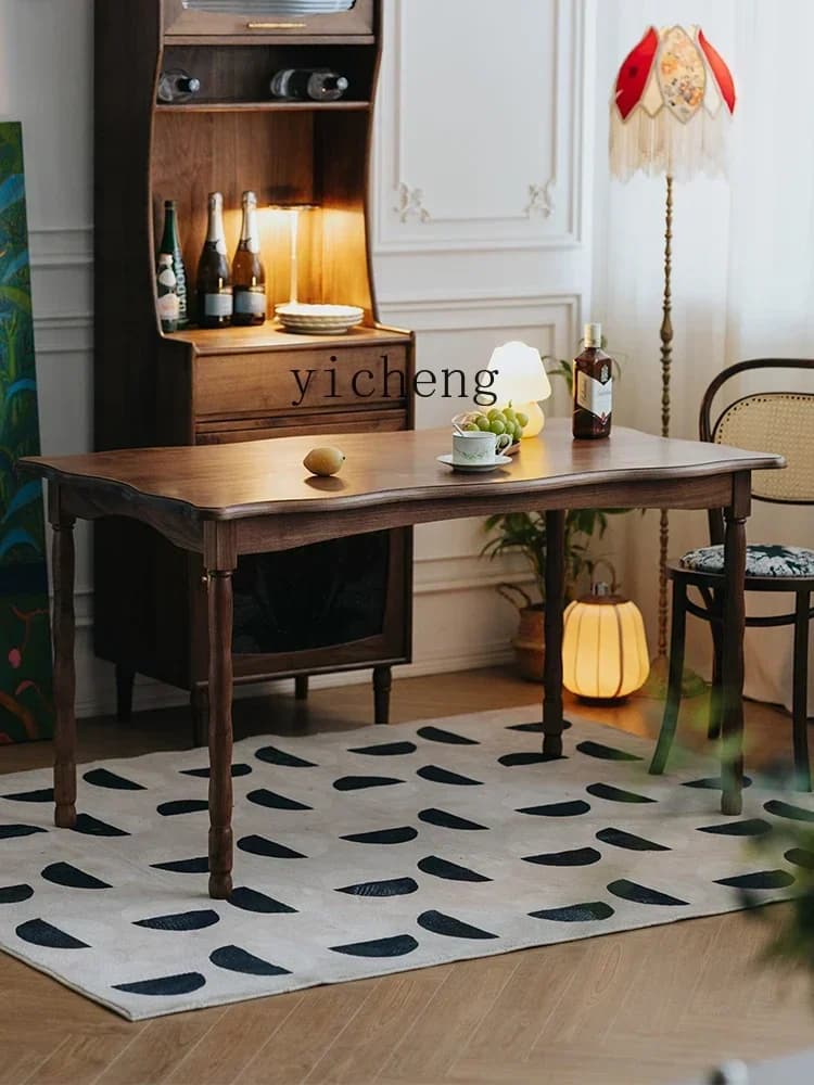 Elegant black walnut solid wood dining table with retro curved edges and tapered legs in a home setting.