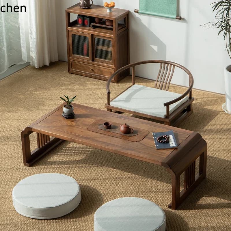 Traditional solid wood tatami low tea table with matching curved chair and floor cushions in a bright tea room.