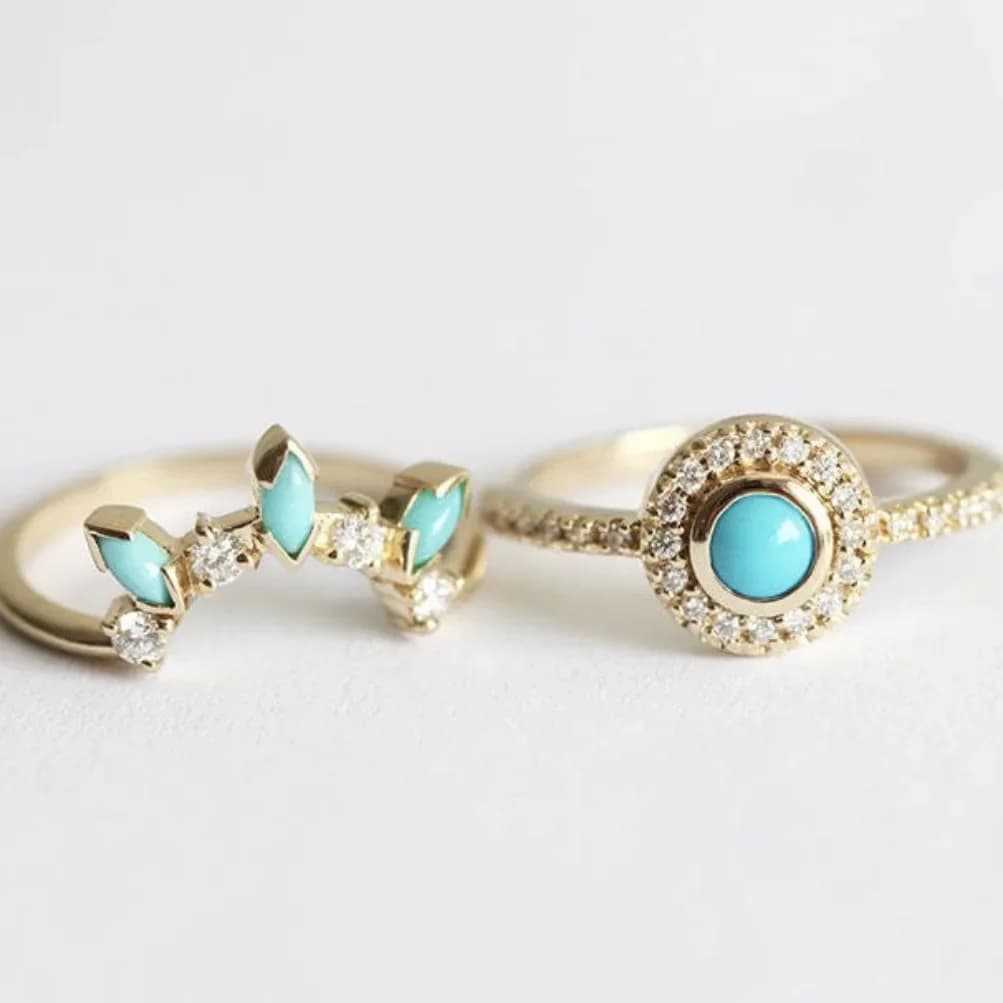 Two vintage-style gold rings featuring vibrant turquoise stones and sparkling accents.