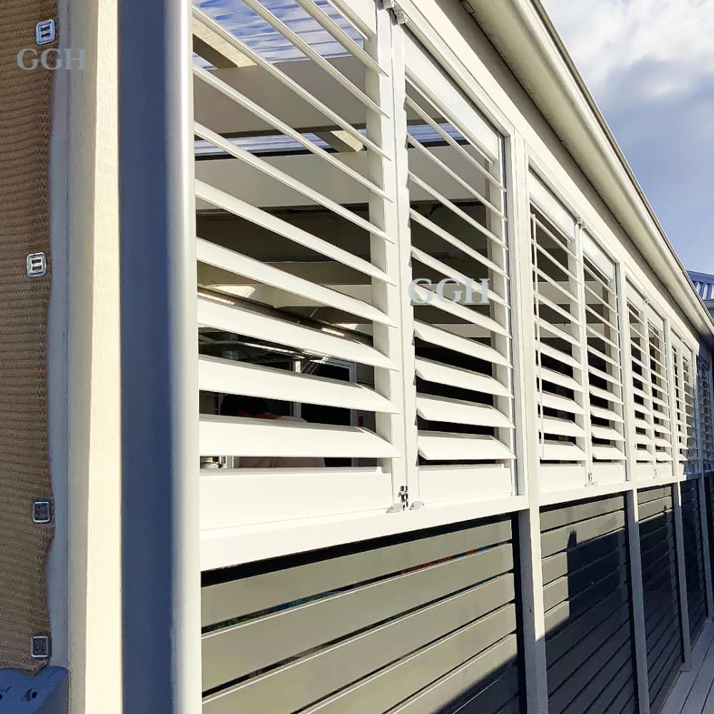 Modern white aluminum horizontal outdoor plantation shutters installed on a patio structure.