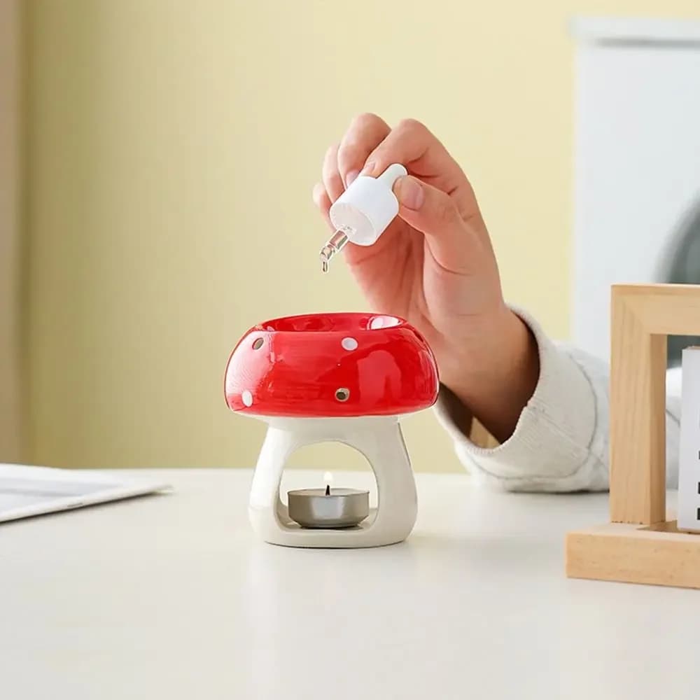 Red mushroom-shaped ceramic oil burner with a white base and a tealight candle inside.