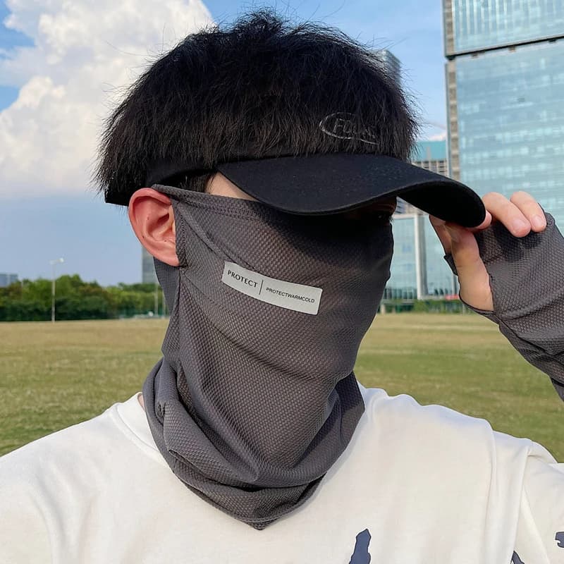 Man wearing a grey ice silk sunscreen mask and black cap for outdoor cycling protection.