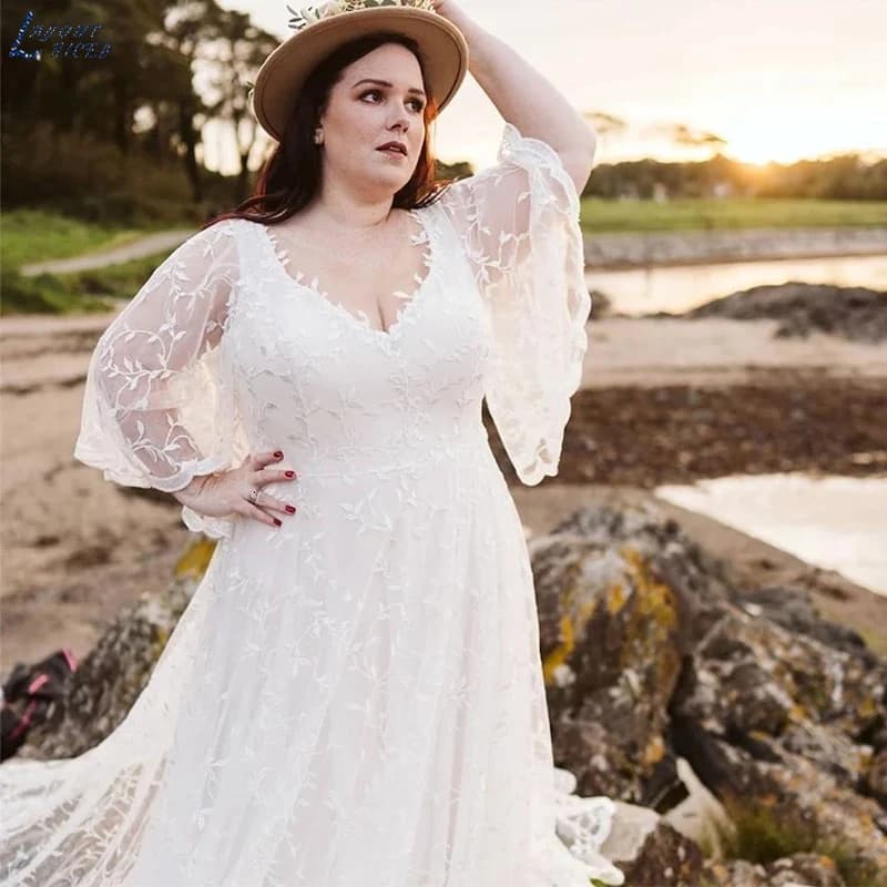 Plus size bride wearing a white lace boho beach wedding dress with bat wing sleeves on a beach.