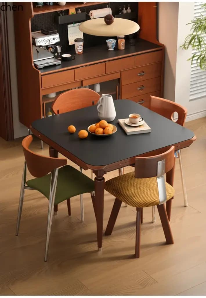 Modern solid wood dining table with a black rock plate top and four stylish chairs in a cozy dining room setting.