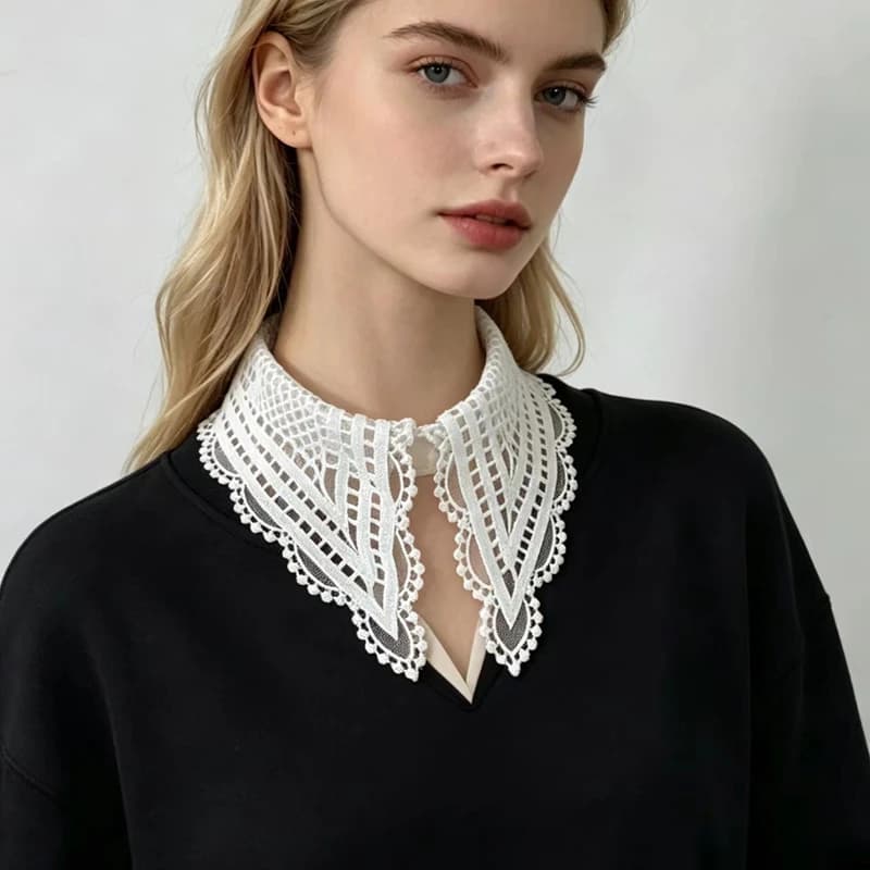 Close-up of a woman wearing an intricate white floral hollow-out embroidered detachable collar over a black sweater.