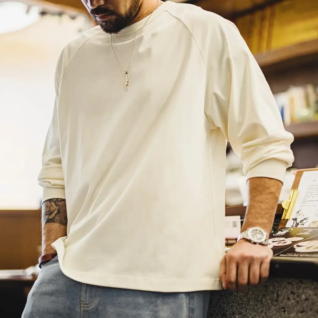 Man wearing a white MADEN long sleeve loose-fit t-shirt with raglan sleeves and a casual look.