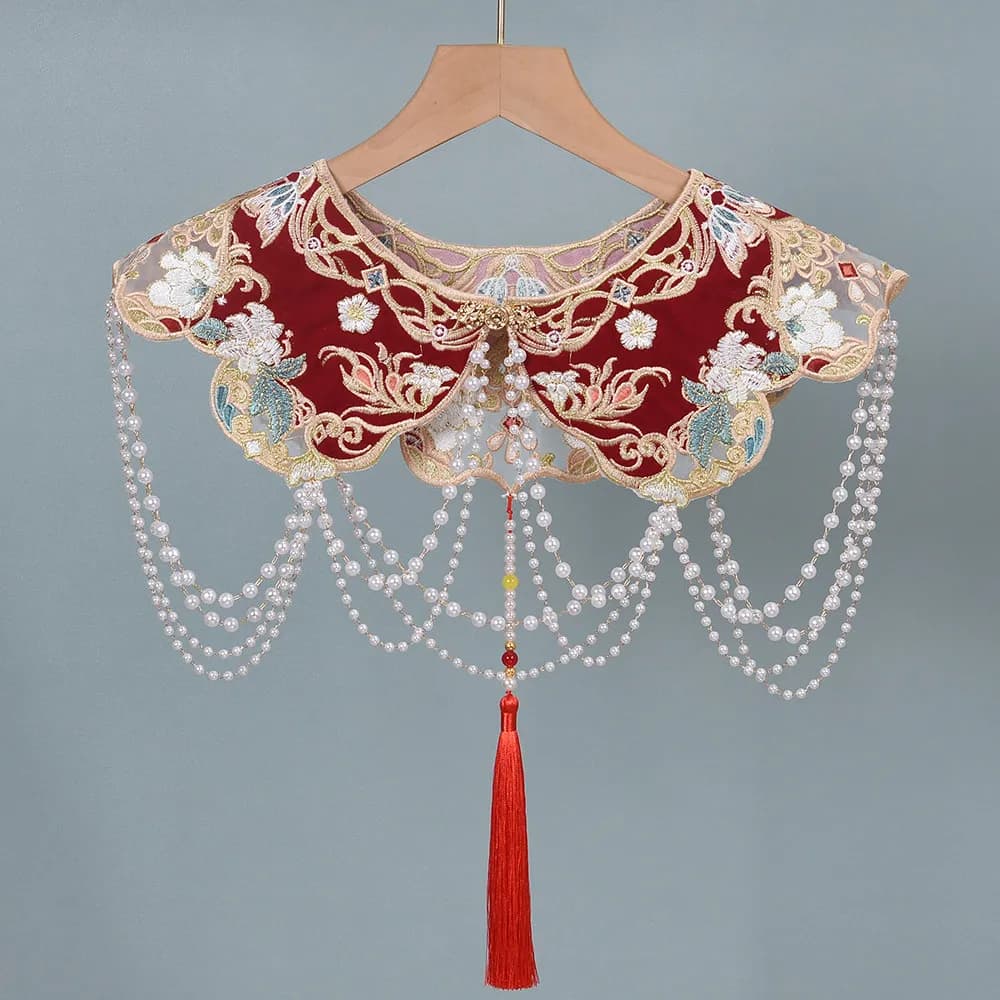 Red Chinese cloud collar with white floral embroidery and hanging pearl tassel strands.